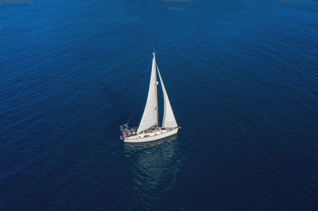 sailing-boat-with-white-sails-rippled-sea-backgro-2022-12-16-12-26-14-utc